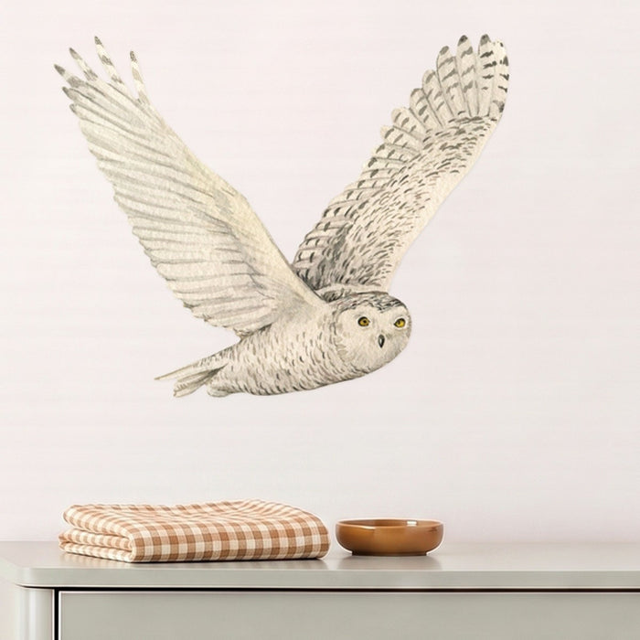 Large snowy owl wall decal flying above a sage dresser in a nursery