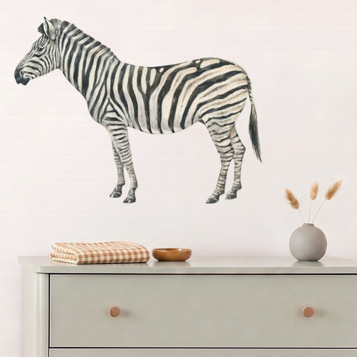 Large zebra wall decal above a sage dresser in a nursery