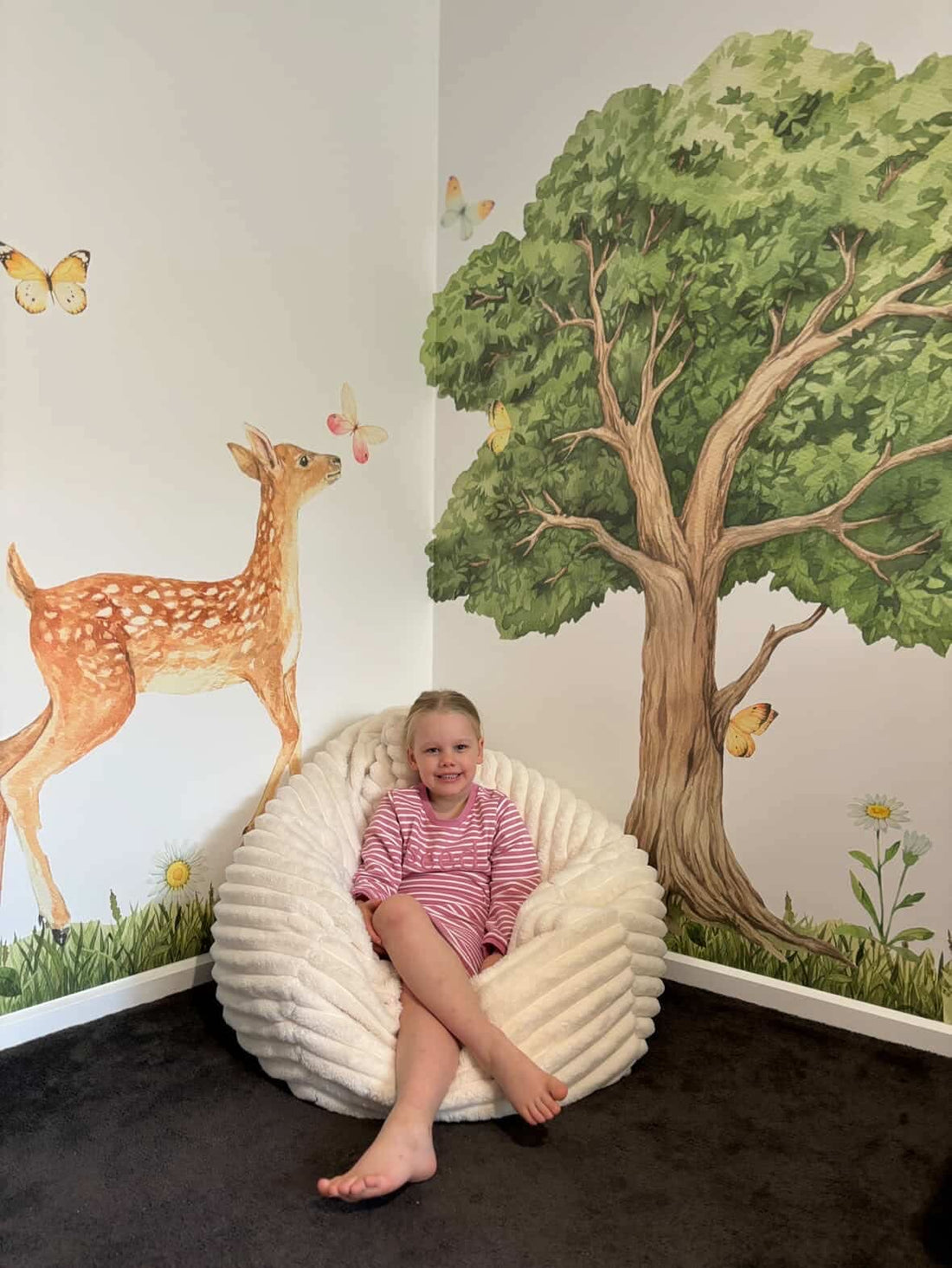 Customer photo of a child beneath an oak tree wall decal with deer and butterflies
