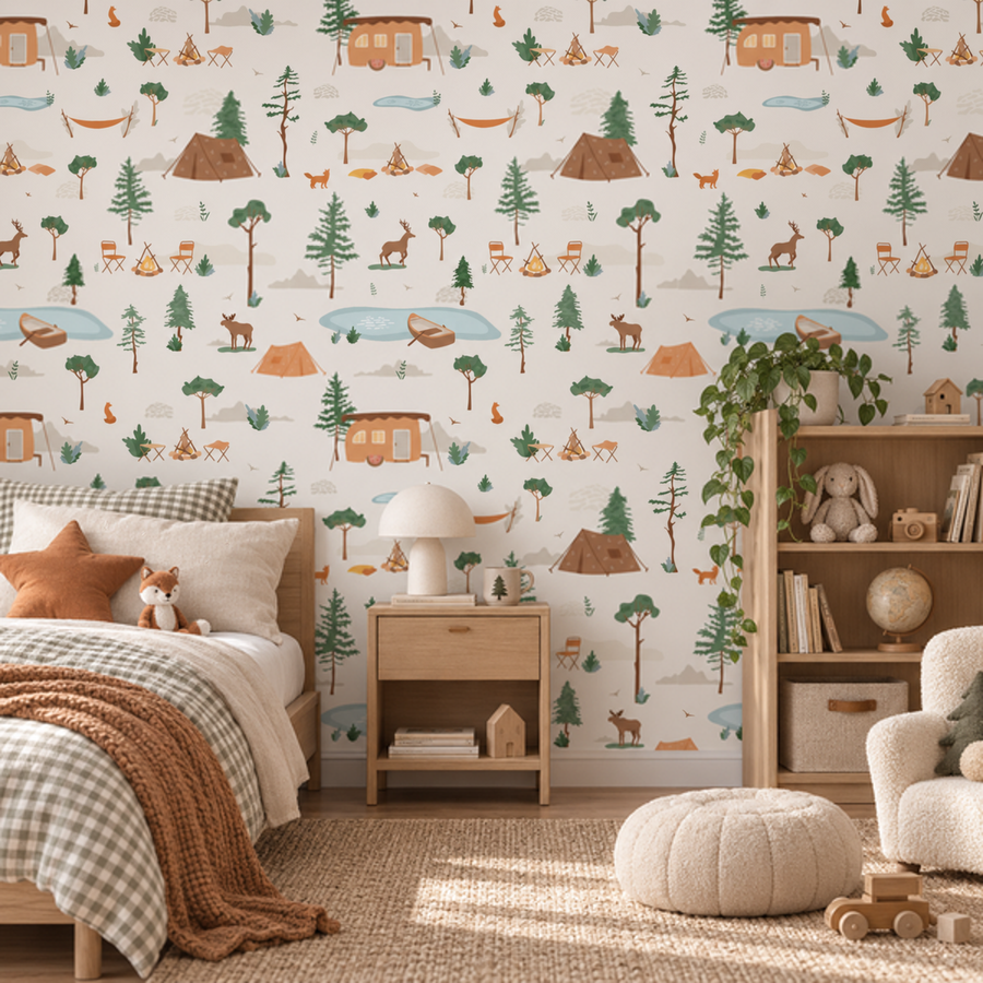 A styled children's bedroom featuring a wall covered in whimsical camping-themed wallpaper with a repeating pattern of trees, cabins, tents, campfires, and animals on a cream background. The room includes a bed with neutral-toned bedding, a wooden nightstand with a white lamp, a plush pouf, a bookshelf, and a chair.