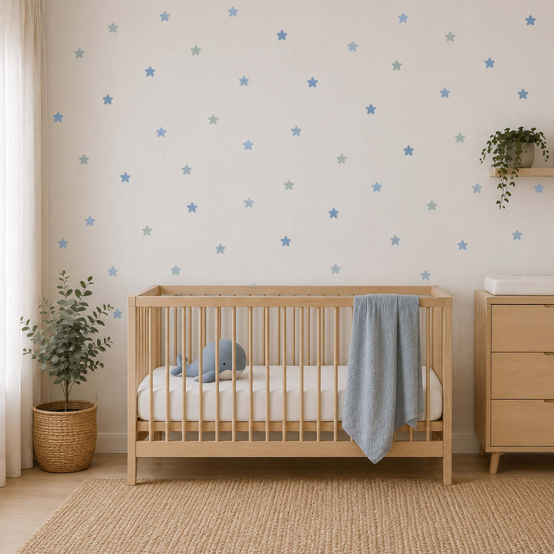 A styled nursery room featuring light blue star decals on an off-white wall behind a light wood crib and matching dresser, with potted plants and a woven rug.