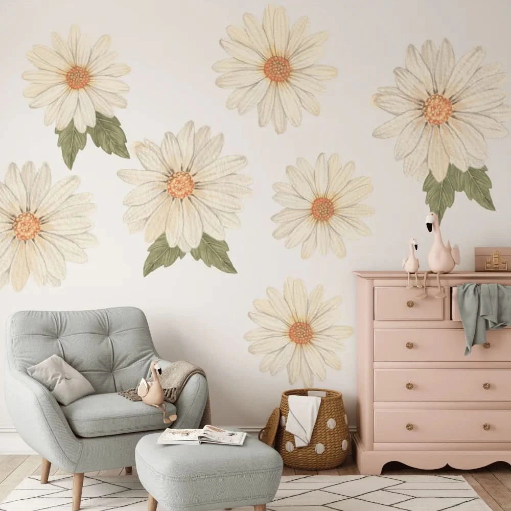 Large daisy wall decals in cream above a grey armchair and pink drawers