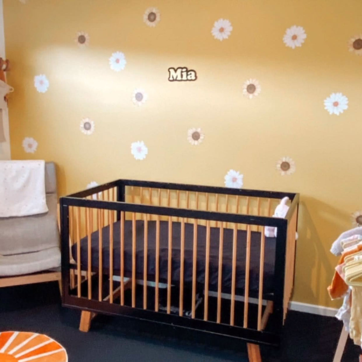 Customer photo of mini daisy decals on a mustard wall with a name decal