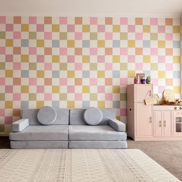 Children's playroom with a checkered wall, gray sofa, and toy kitchen.