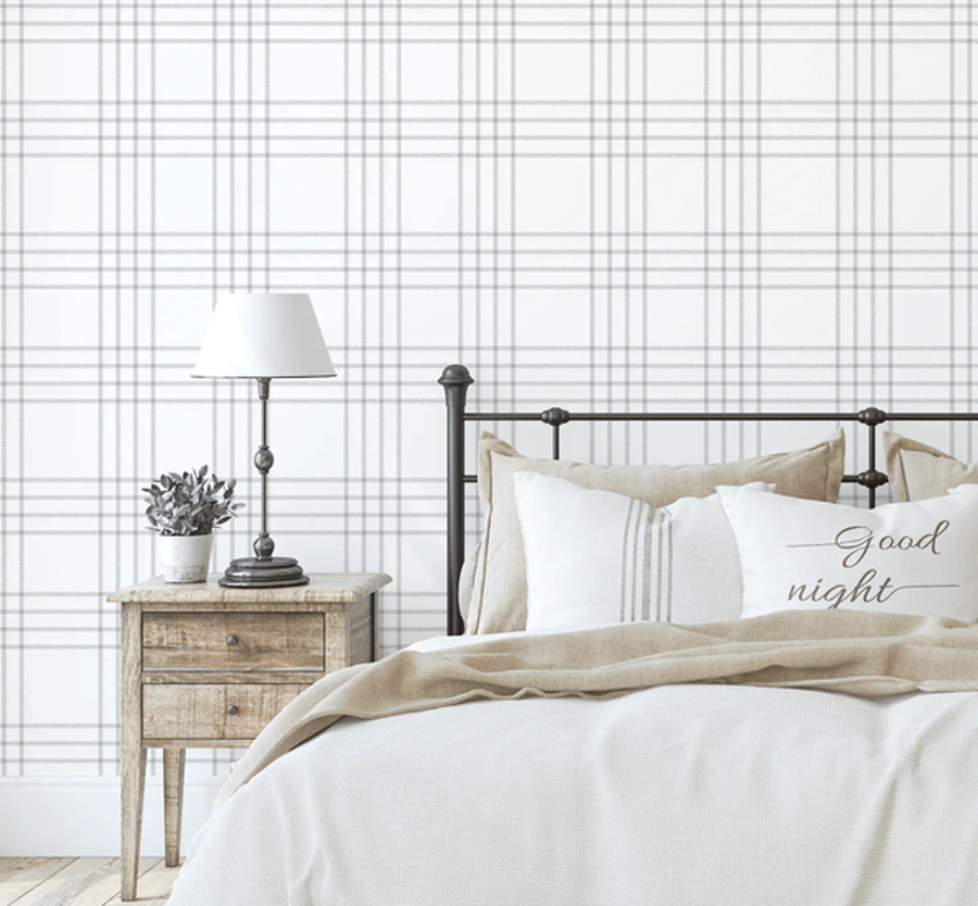 Alan Grey Plaid Farmhouse wallpaper behind a bed with a timber bedside table and lamp