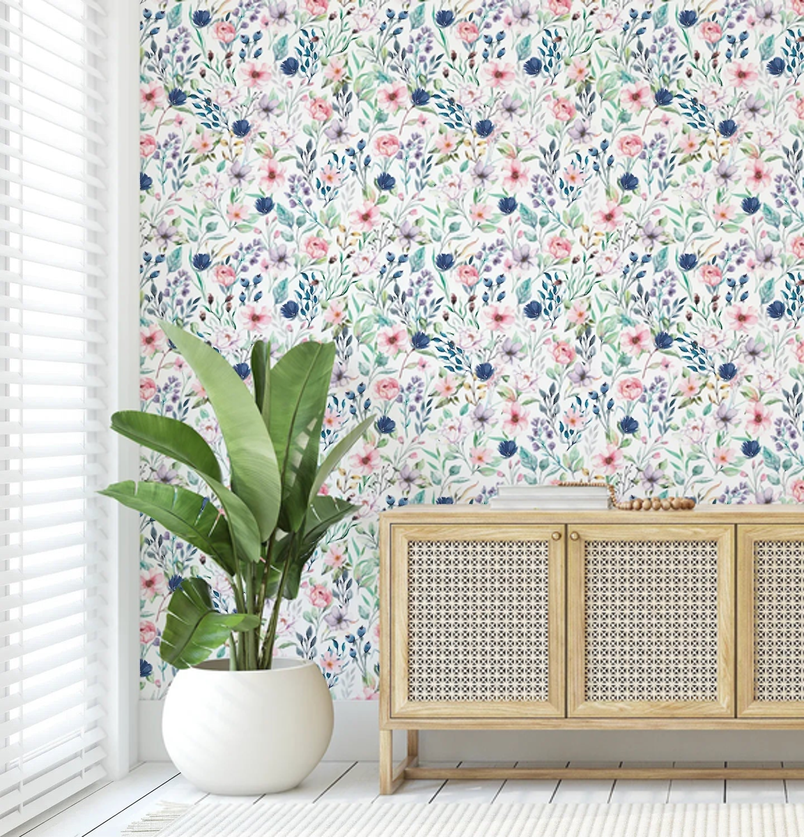 Blooming Paradise floral wallpaper behind a cane sideboard and potted palm