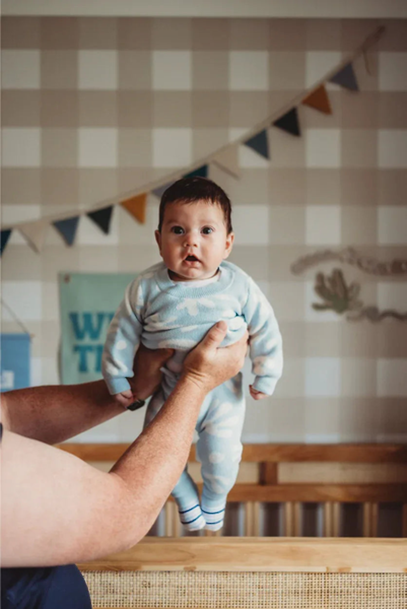 Baby held in front of a Jumbo Traditional Gingham Wheat wallpaper wall with bunting