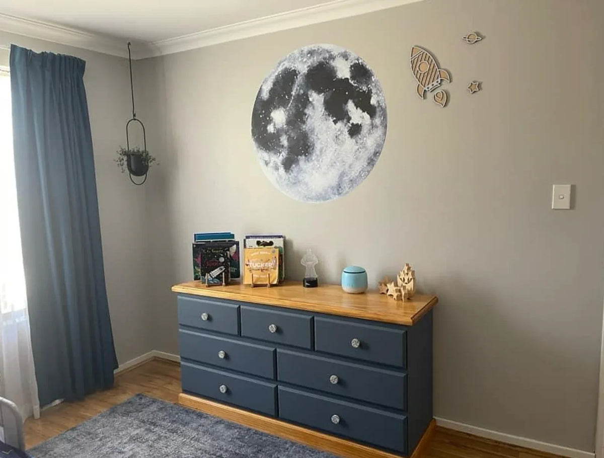 Customer photo of the moon wall decal above a navy dresser