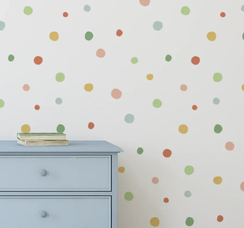 Multicolour spot decals scattered on a wall above a pale blue dresser