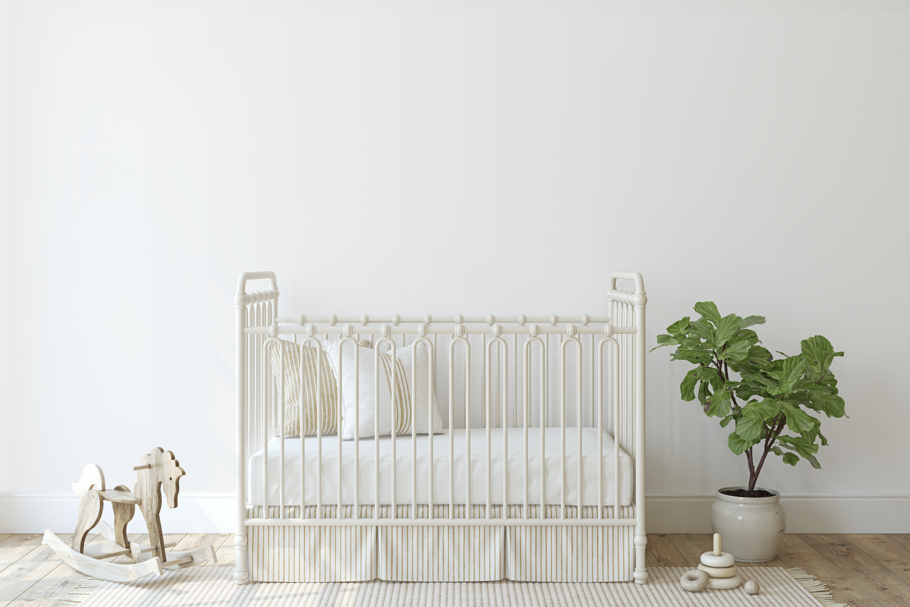 White crib in a minimalistic room with a plant and toys on a light wooden floor.