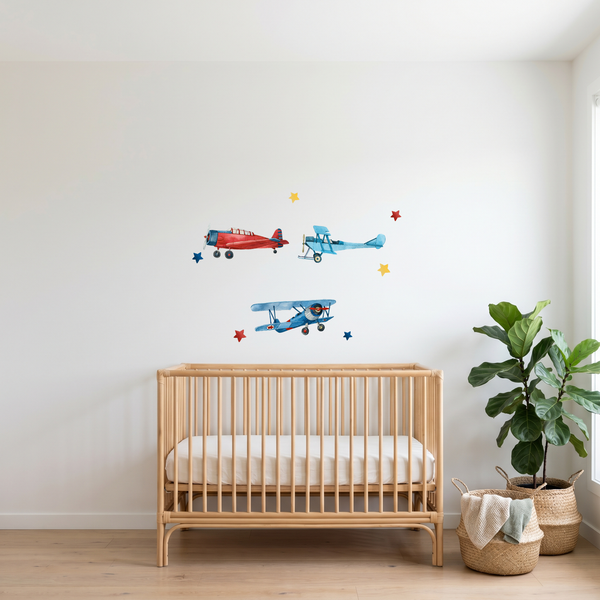 Nursery room with wooden crib, wall stickers of airplanes, and a plant.