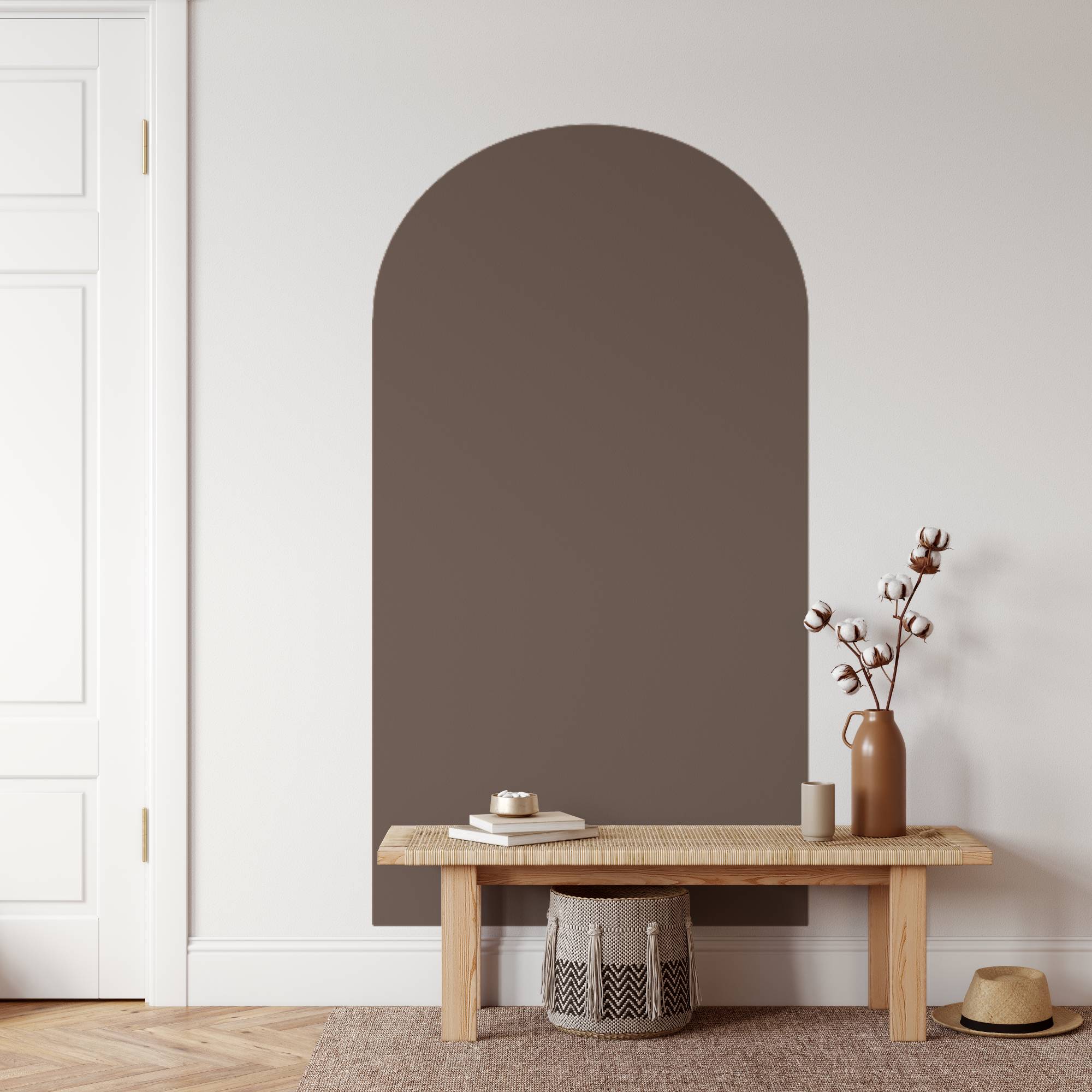 Arch-shaped mirror on a wall with a wooden bench and decorative items below.