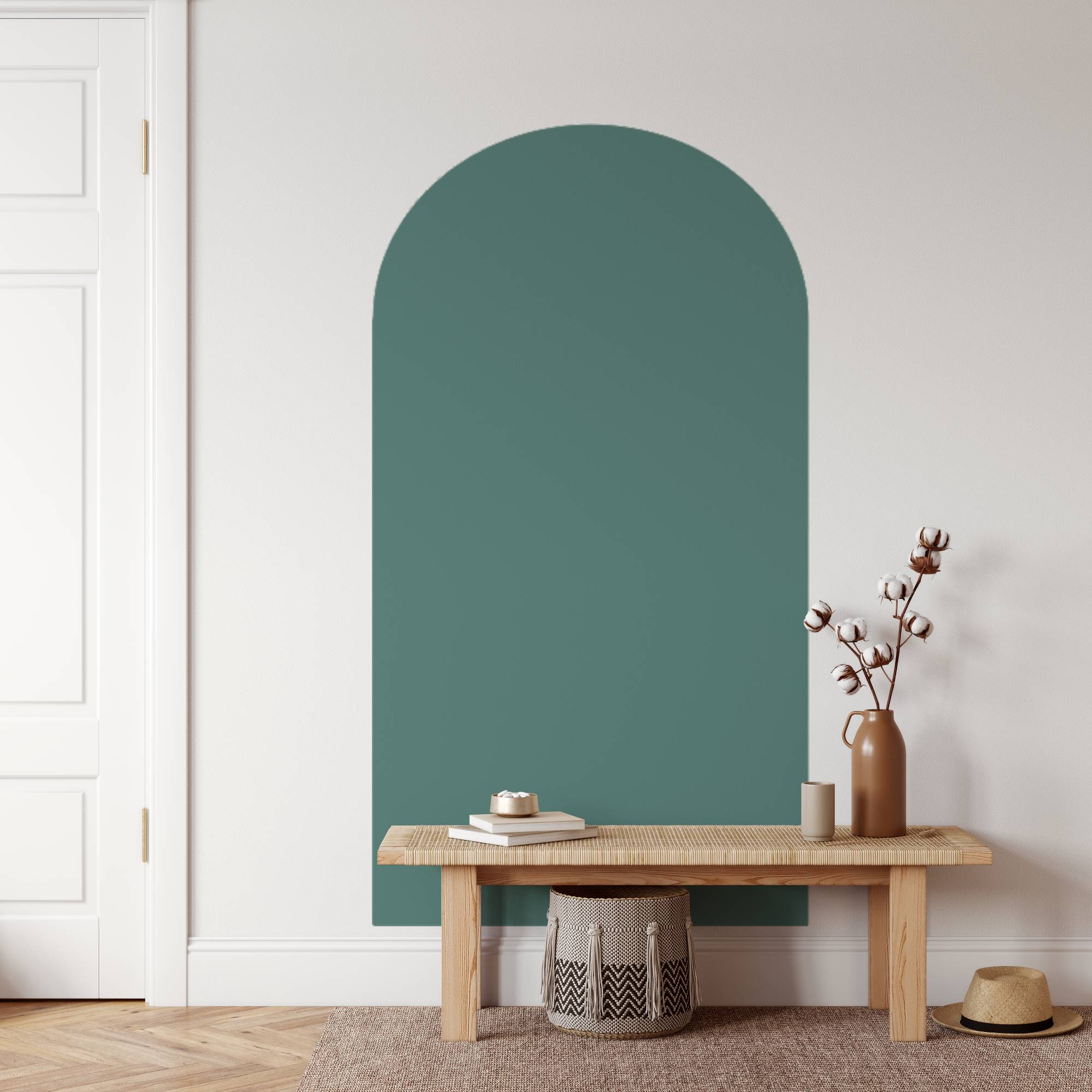 Teal arched mirror on a white wall with a wooden bench and decorative items.