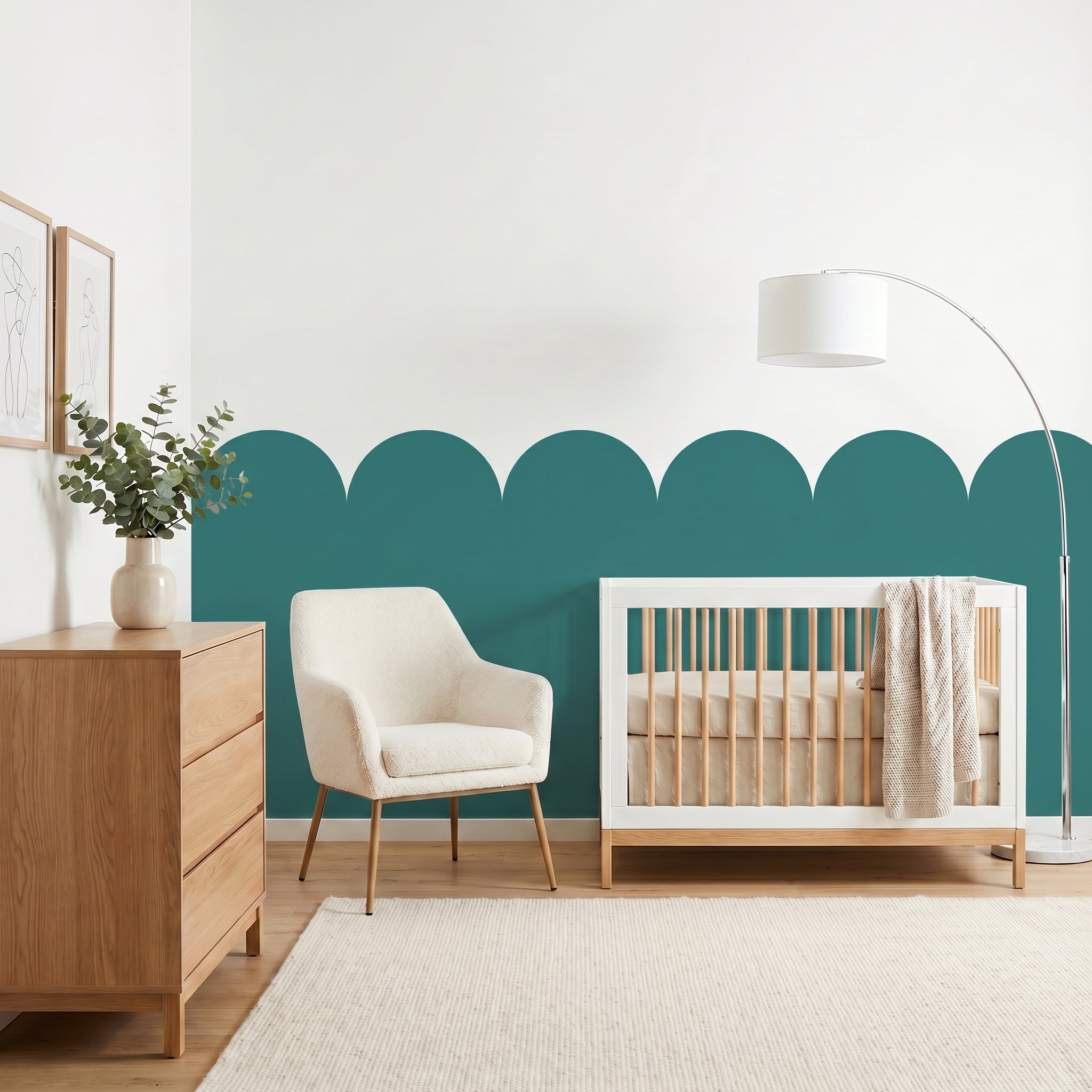 Nursery room with a crib, chair, and dresser against a teal accent wall.