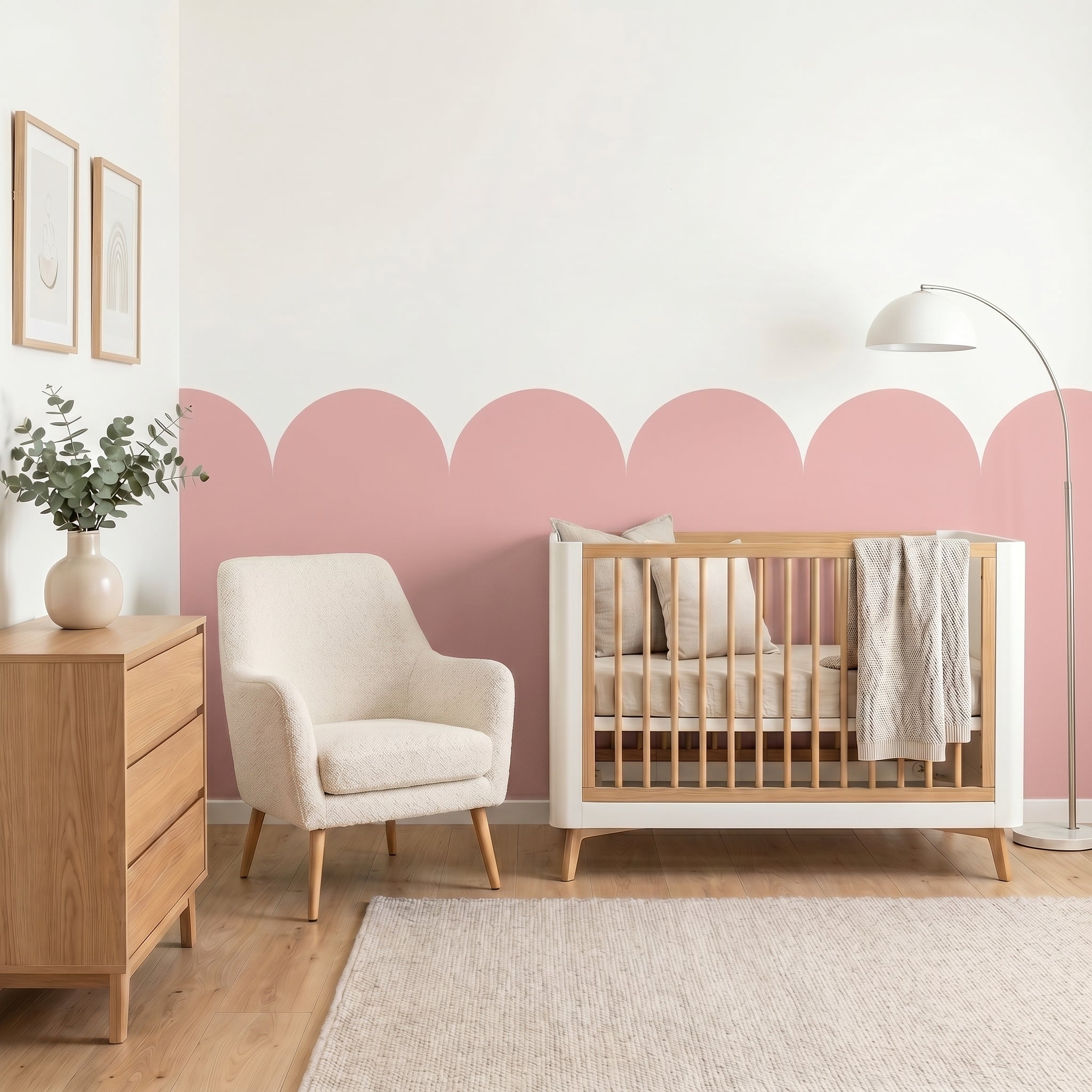 Nursery room with wooden crib, white armchair, and pink accent wall.