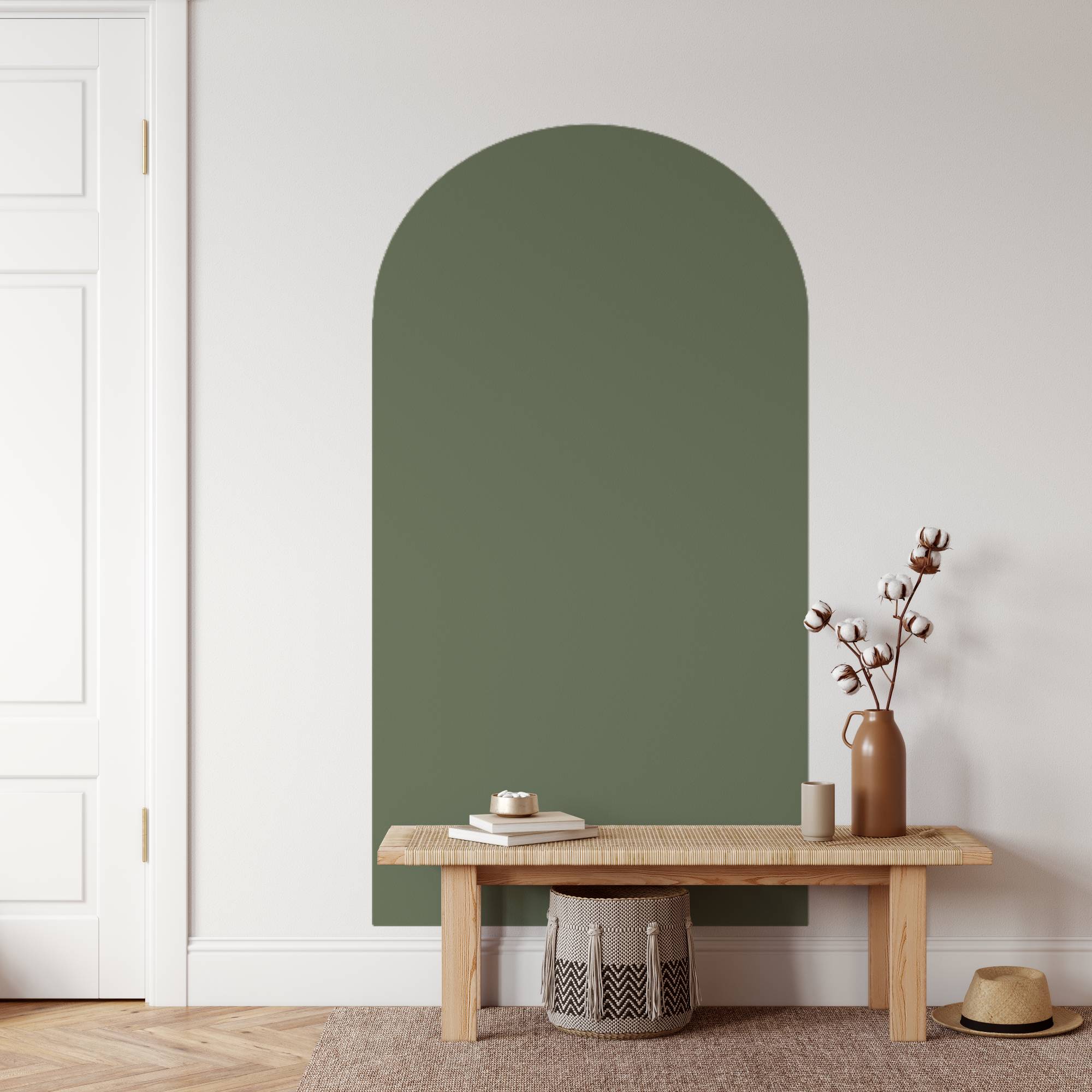 Green arched mirror on a white wall with a wooden bench and decorative items below.
