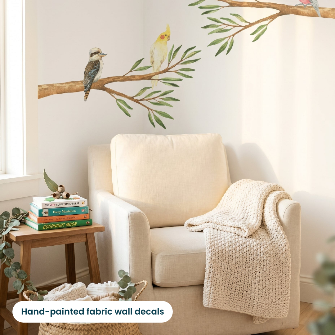 Hand-painted gum branch wall decal with a kookaburra and cockatiel above a reading armchair