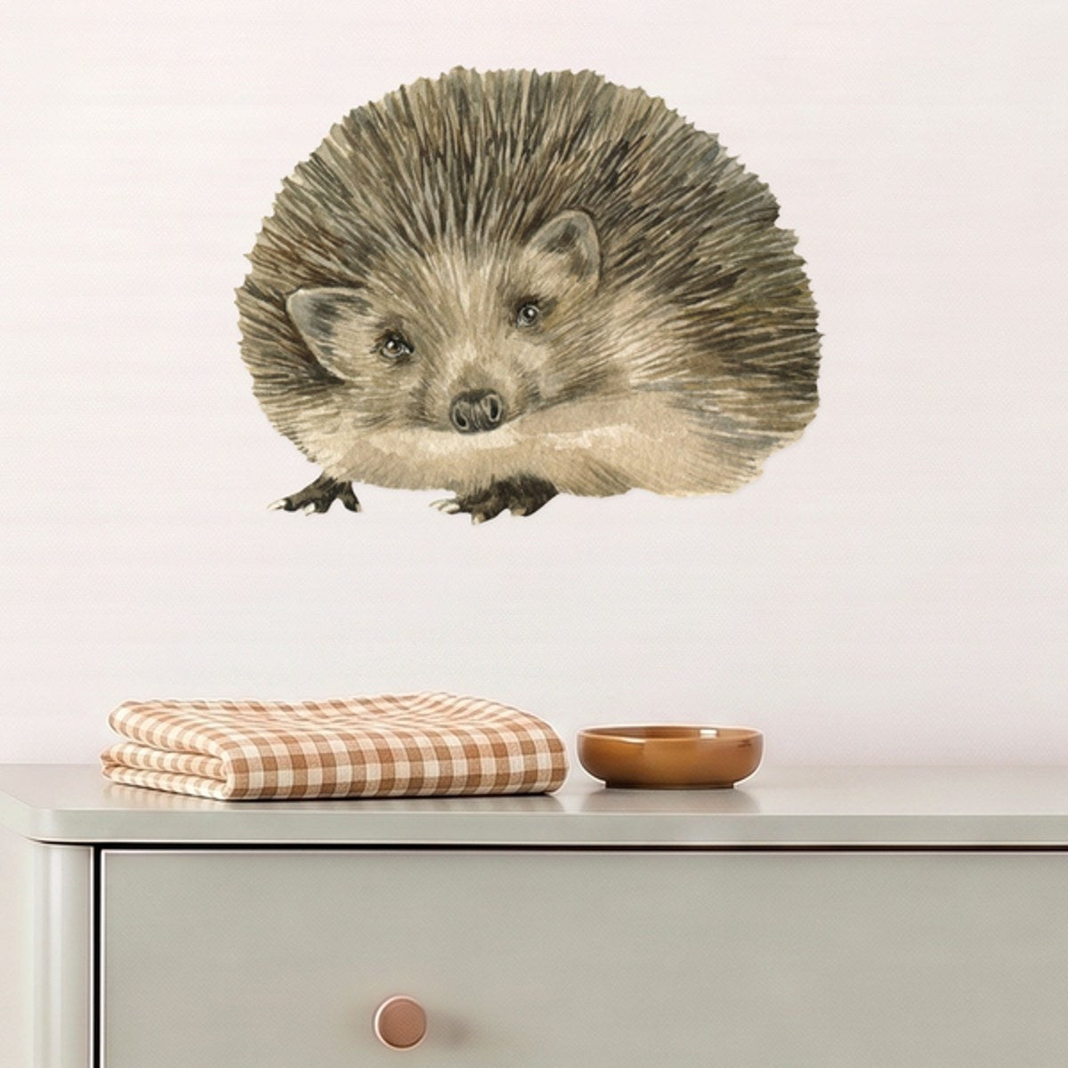 Large hedgehog wall decal above a sage dresser in a nursery