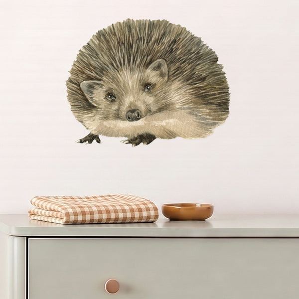 Large hedgehog wall decal above a sage dresser in a nursery
