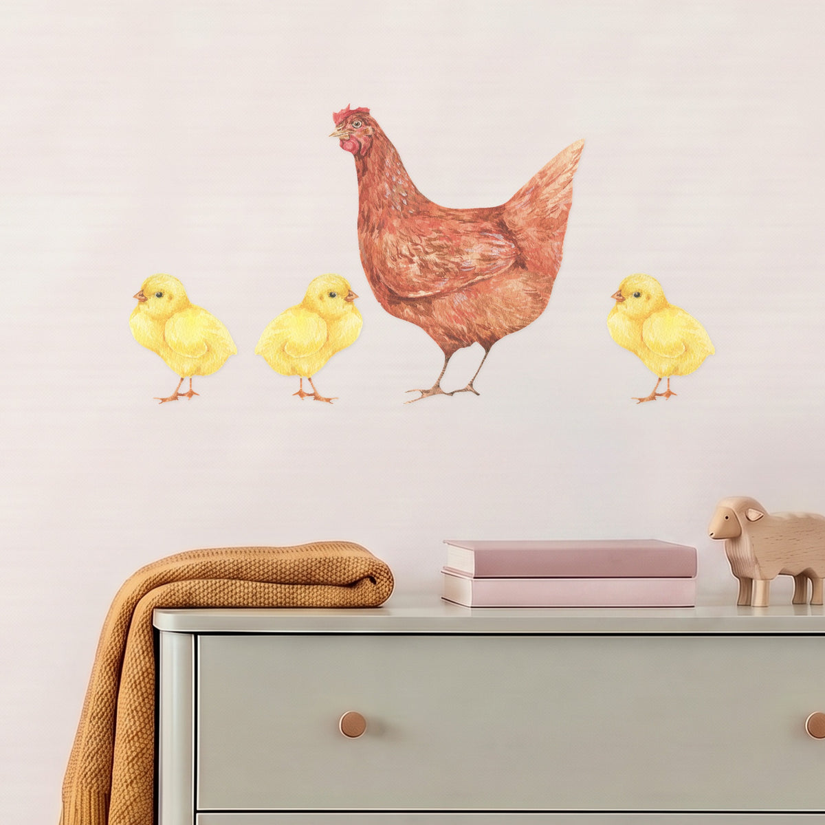Large hen and three chicks wall decal above a sage chest of drawers in a nursery