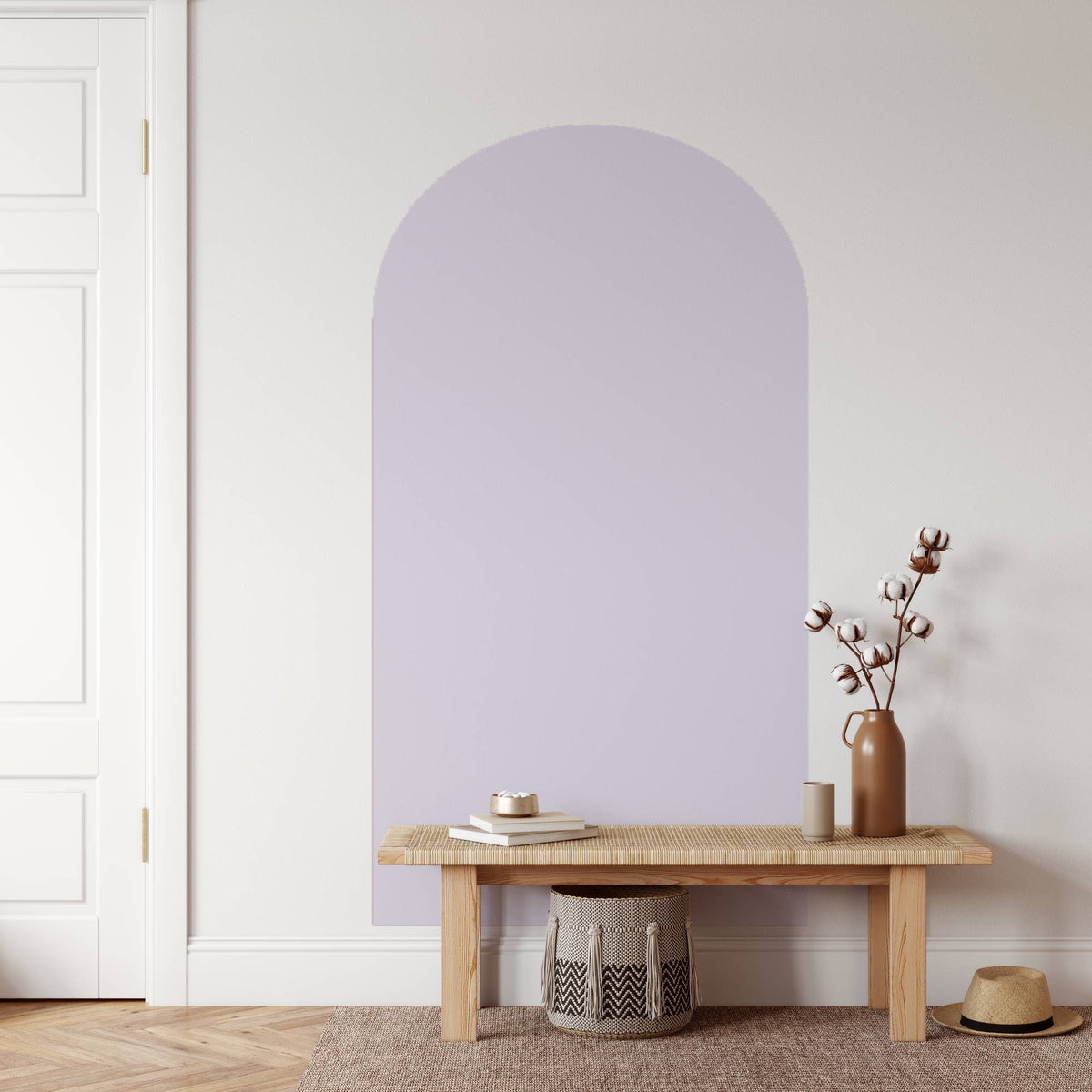 Wooden bench with a vase and books against a light purple wall.