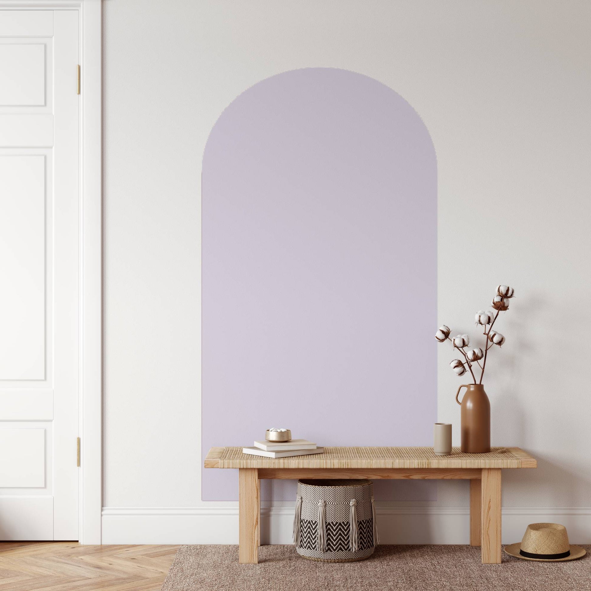 Wooden bench with a vase and books against a light purple wall.
