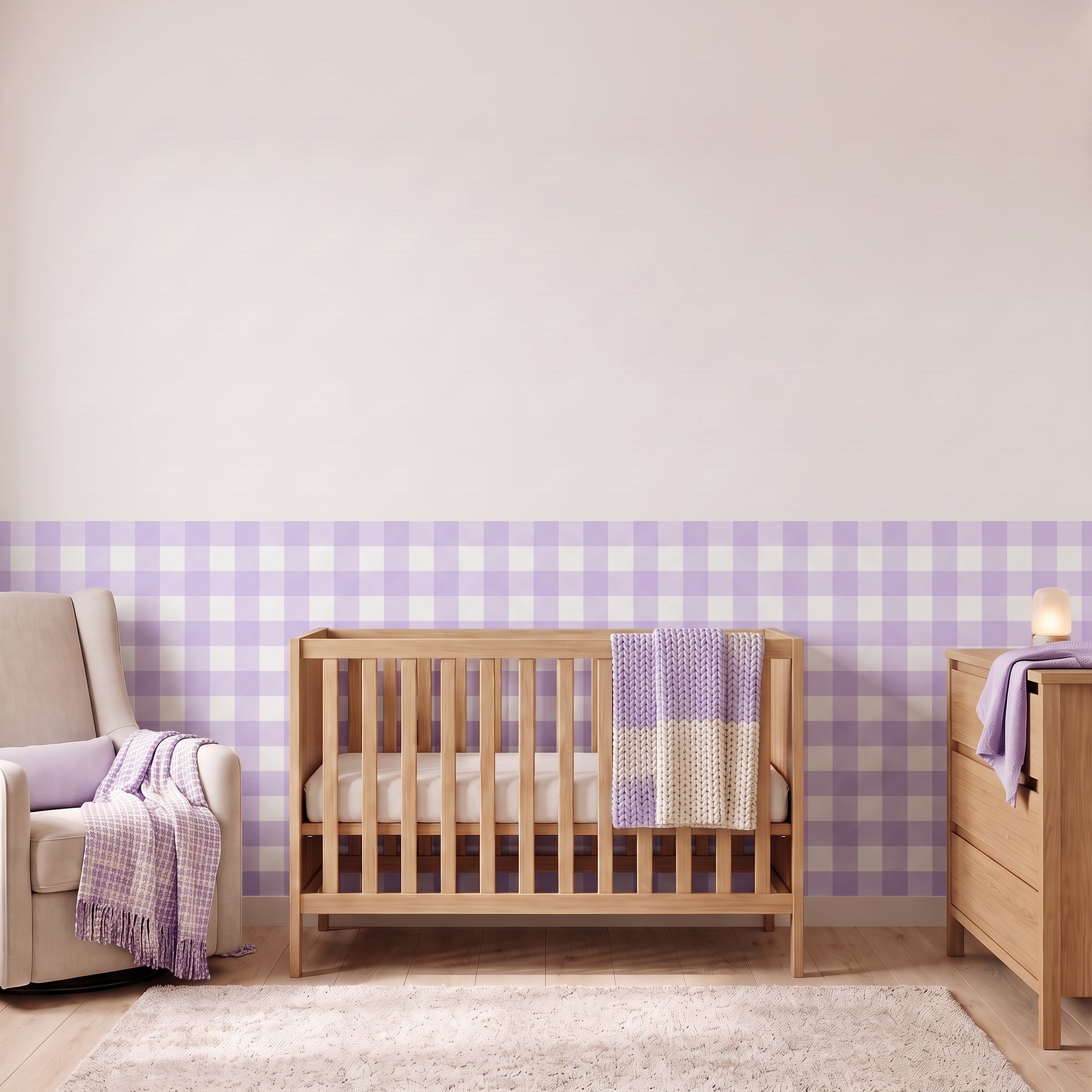 A styled nursery with lavender gingham check wallpaper across the lower half of the wall. The room has a light wood crib with white bedding and a lavender and cream blanket, a cream armchair with a lavender woven throw, a matching wood dresser with a lamp, and a soft rug on a light wood floor.