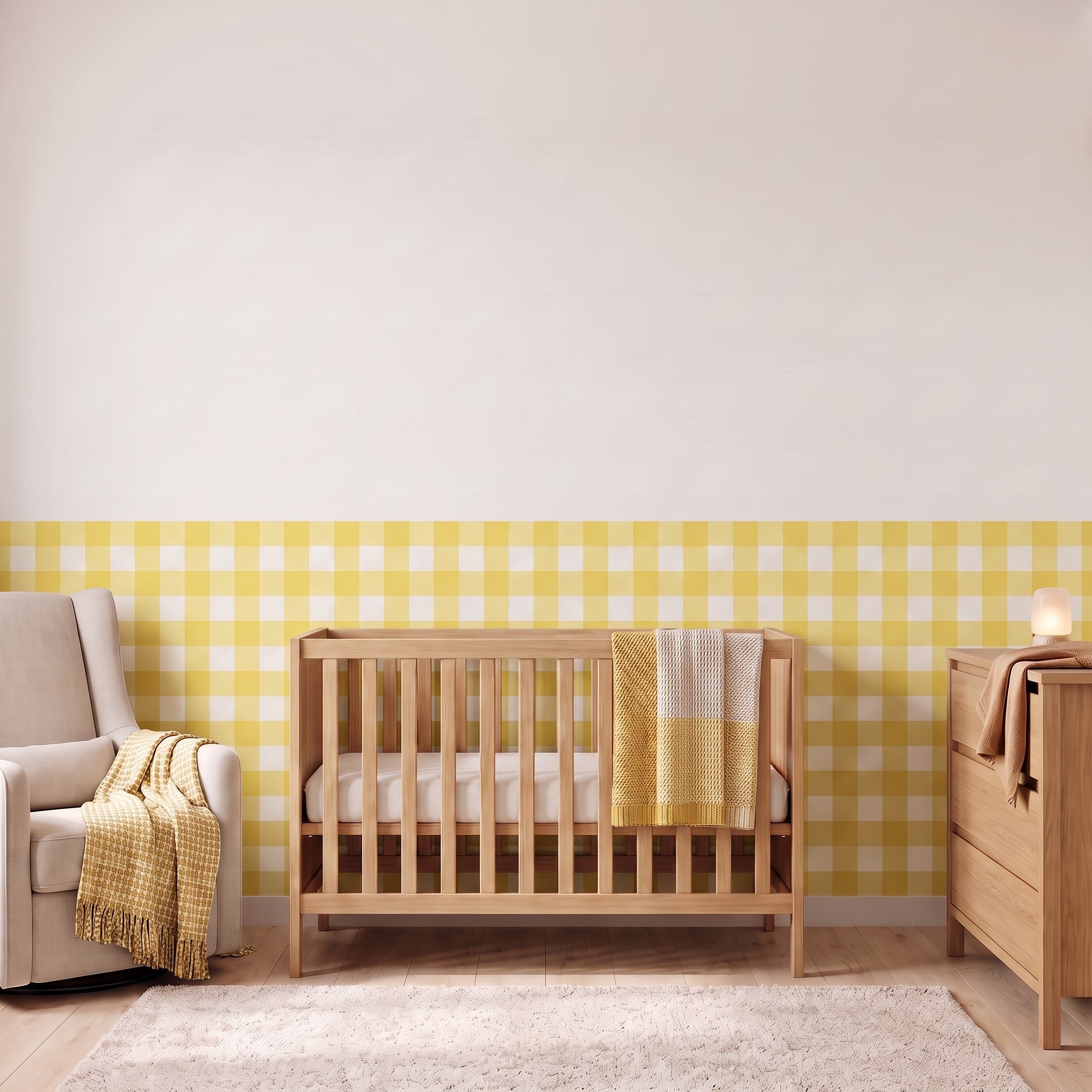A styled nursery with lemon yellow gingham check wallpaper across the lower half of the wall. The room has a light wood crib with white bedding and a lemon and cream checked blanket, a cream armchair with a lemon and cream fringed throw, a matching light wood dresser with a lamp, and a soft cream rug on a light wood floor.