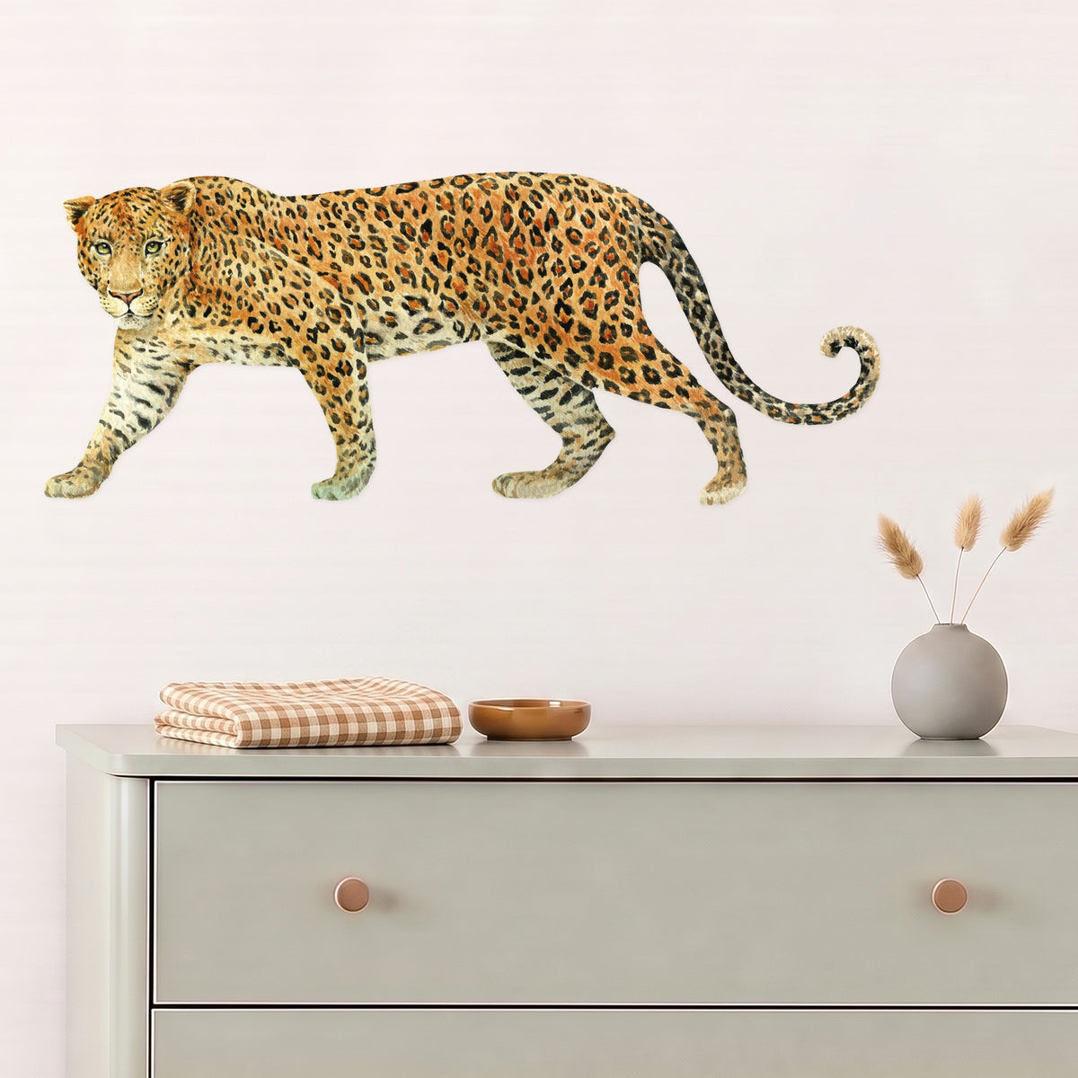 Leopard wall decal above a sage chest of drawers in a nursery