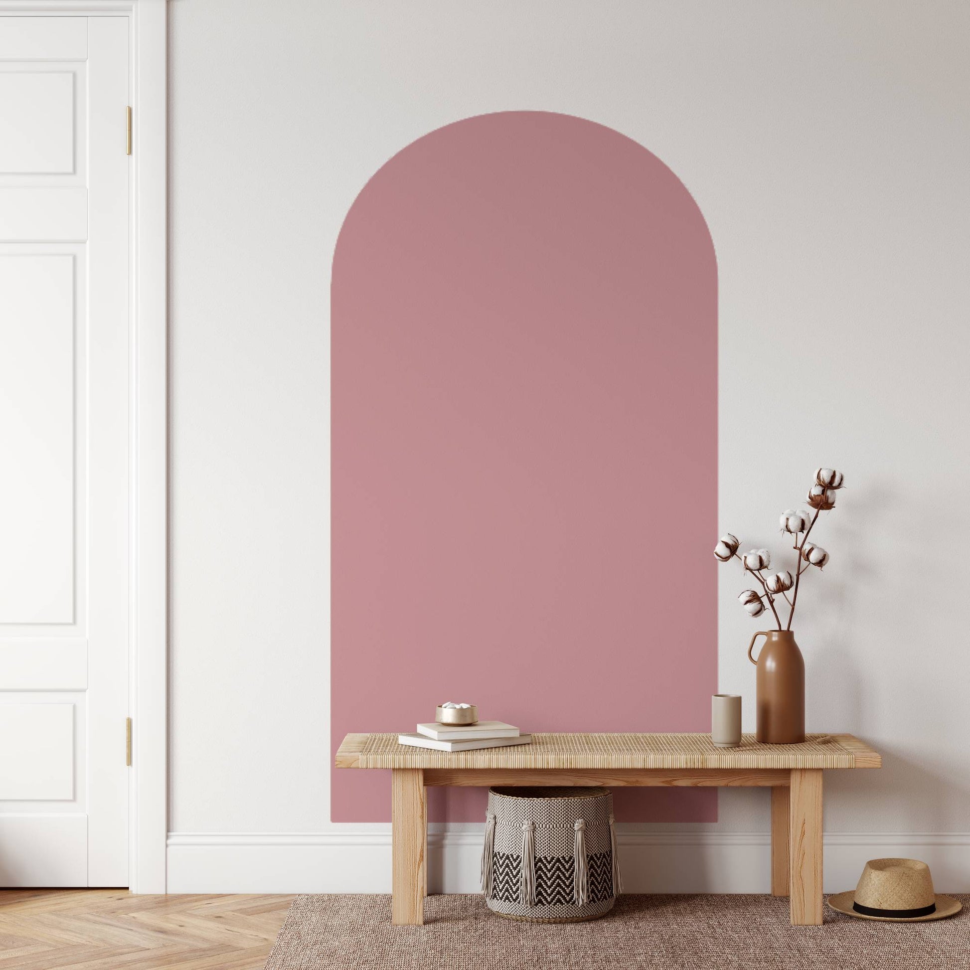 Wooden bench with decorative items against a white wall with an arch-shaped pink panel.