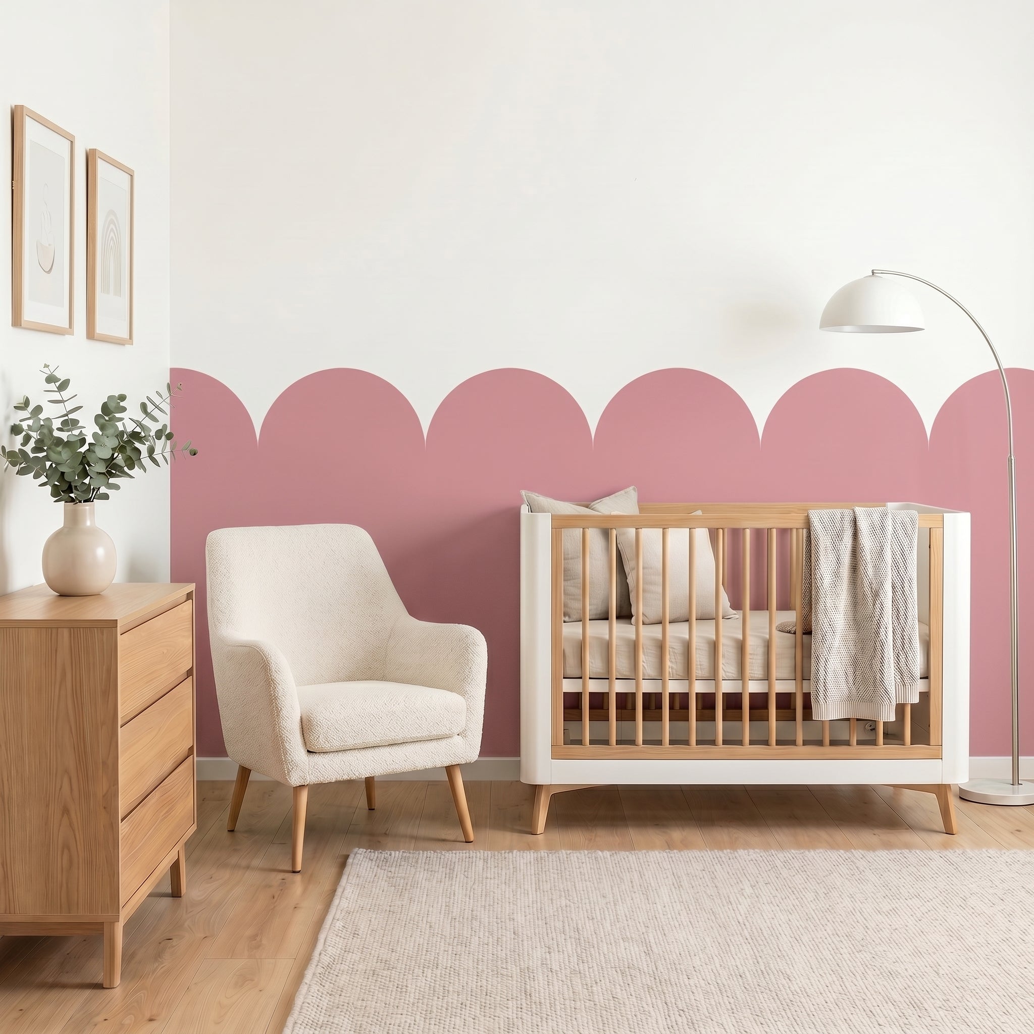 Nursery room with wooden crib, white armchair, and pink accent wall.