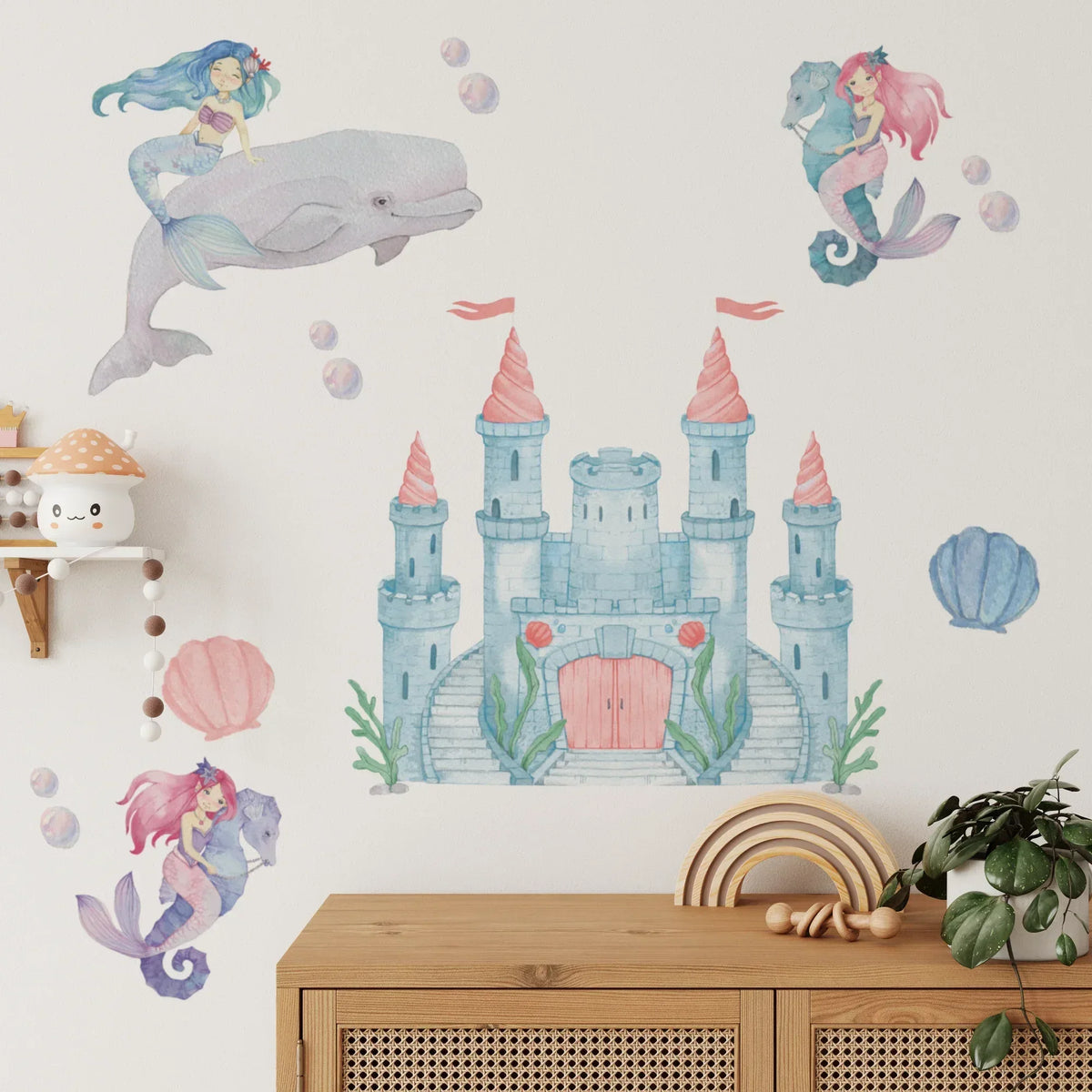 Mermaid wall decals with a whale, castle and seahorse above a cane sideboard