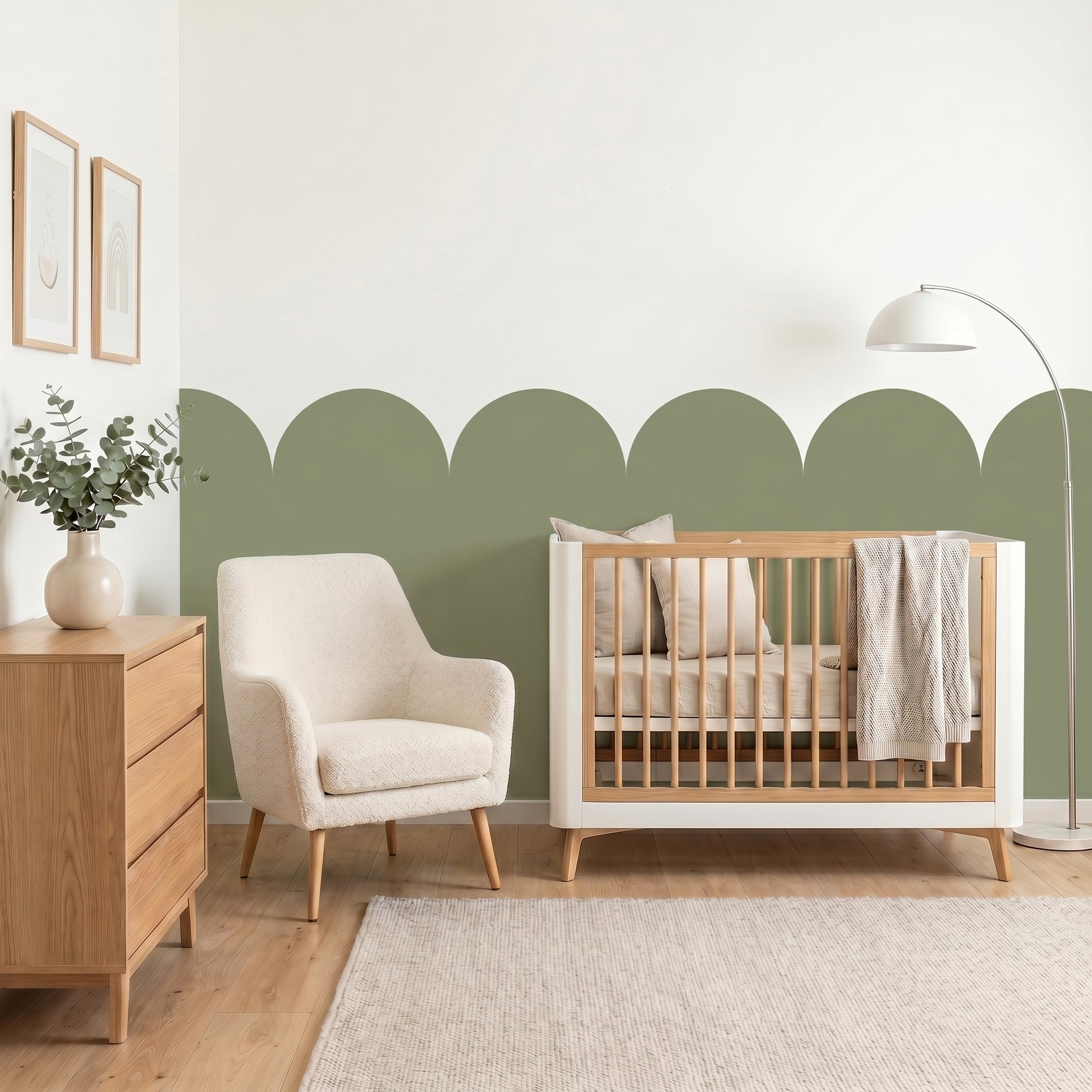 Nursery room with wooden crib, armchair, and dresser against a green and white wall.