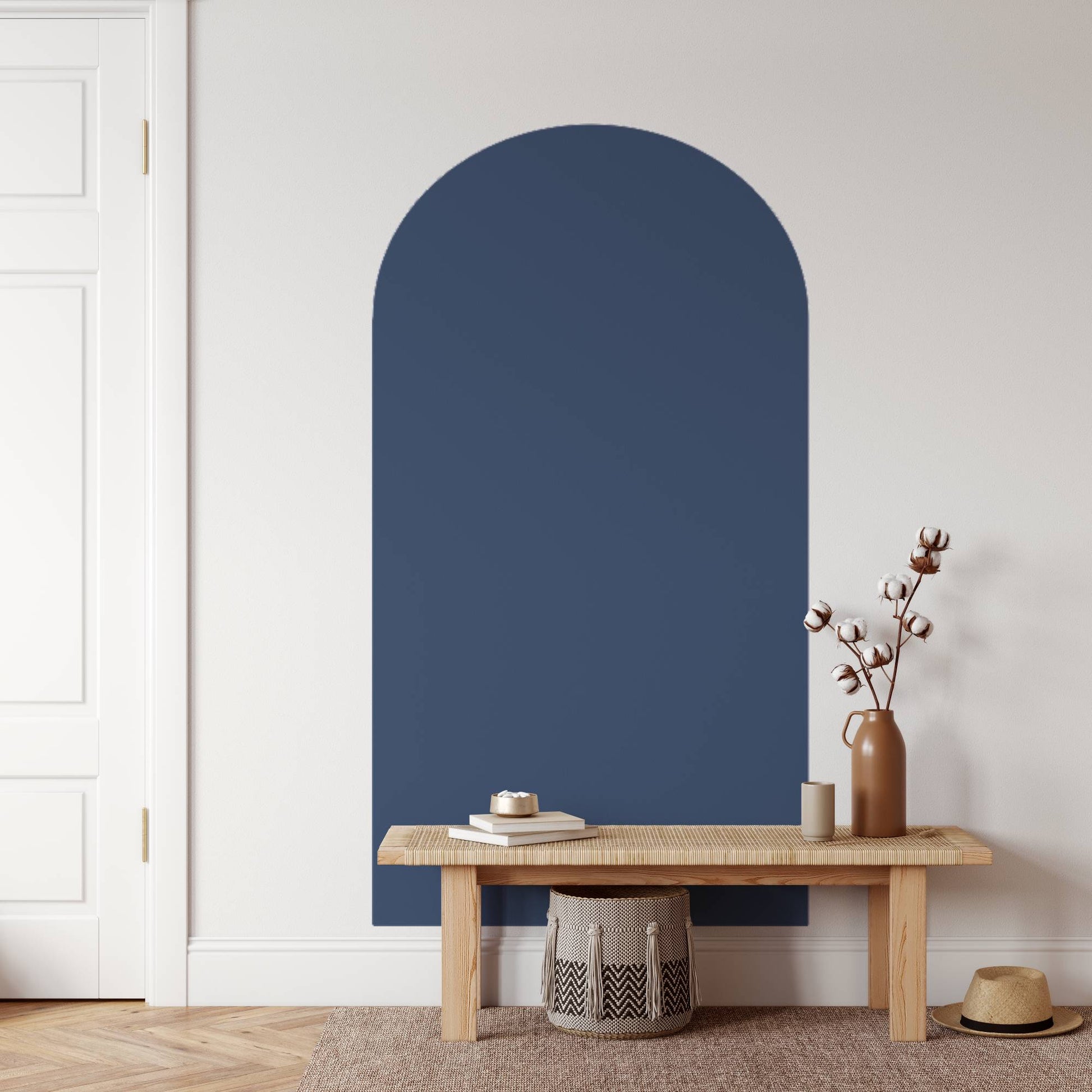 Navy blue arch-shaped wall mirror above a wooden bench with decor items in a room.
