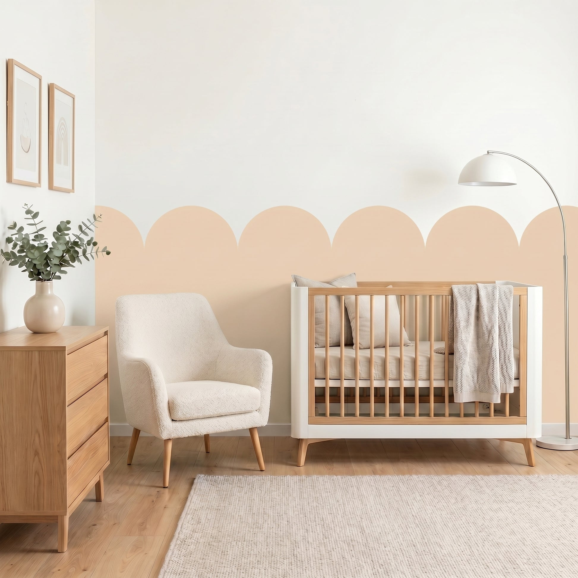 Nursery room with wooden crib, white armchair, and dresser against a scalloped wall.