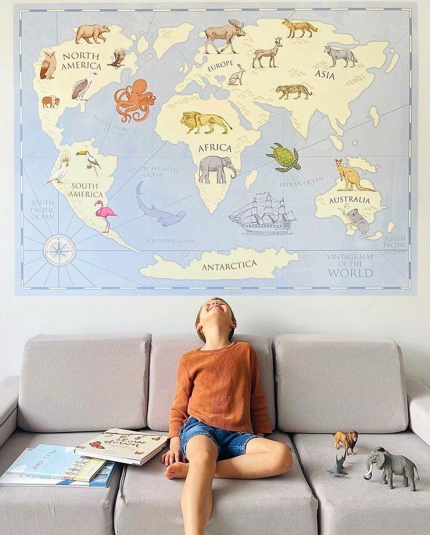 Child sitting in front of the vintage world map wall decal