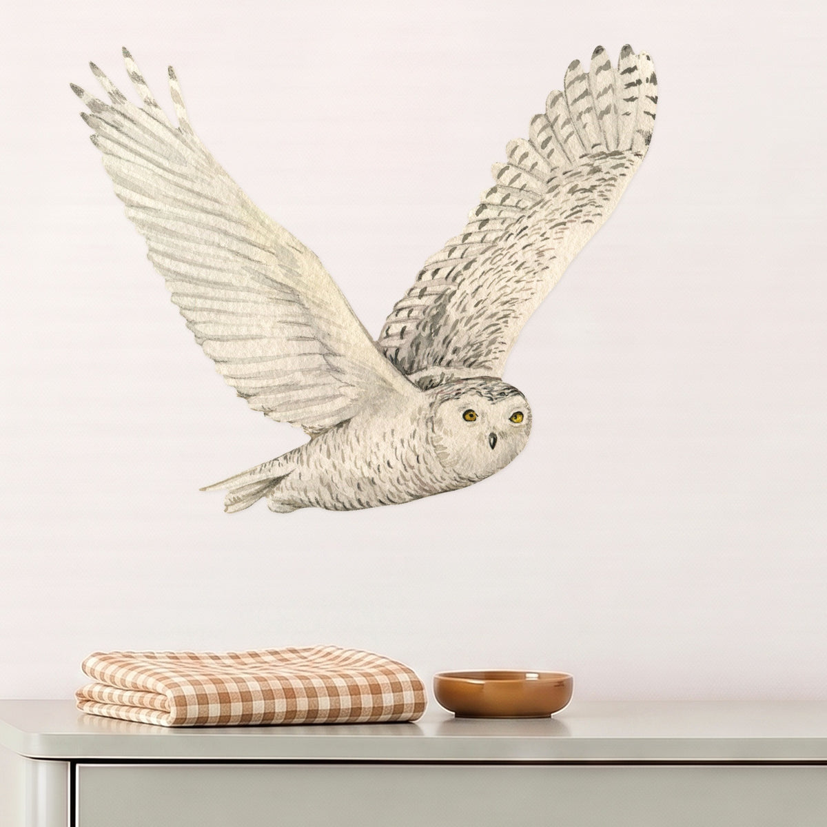 Large snowy owl wall decal flying above a sage dresser in a nursery