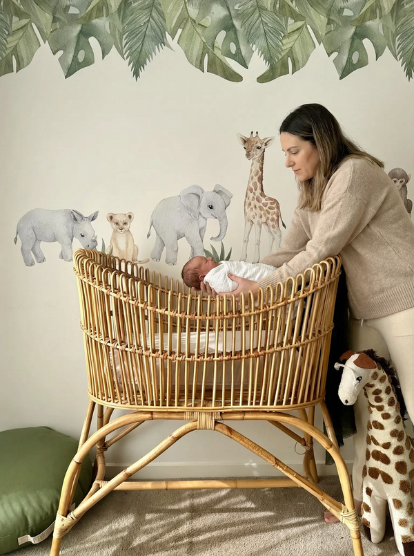 Woman interacting with a baby in a rattan crib with animal-themed wall decor.