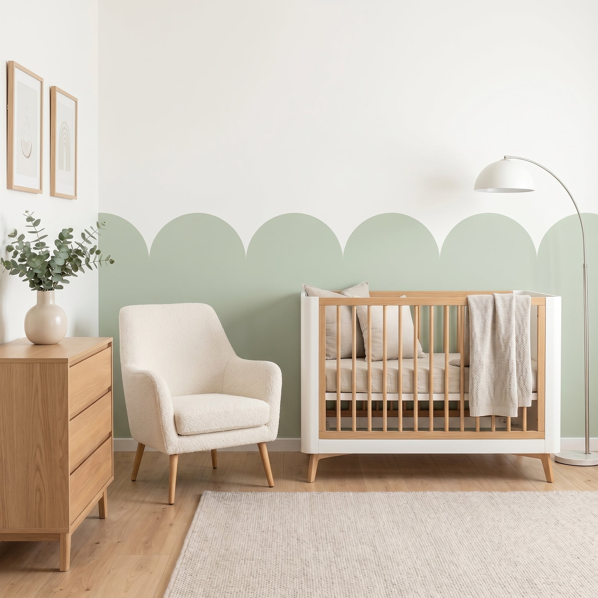 Nursery room with wooden crib, white armchair, and dresser against a light green wall.
