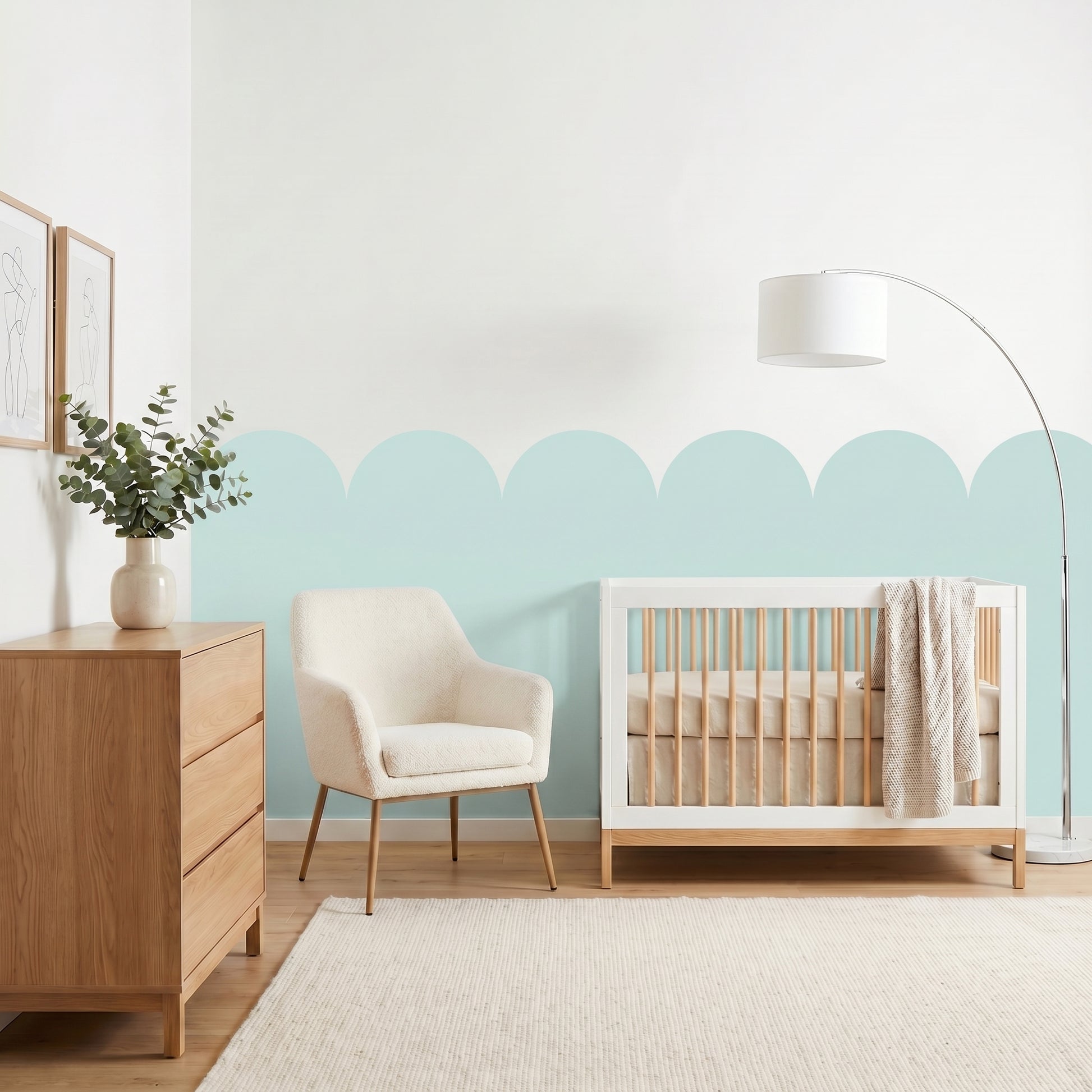 Nursery room with wooden crib, chair, and dresser against a light blue wall.