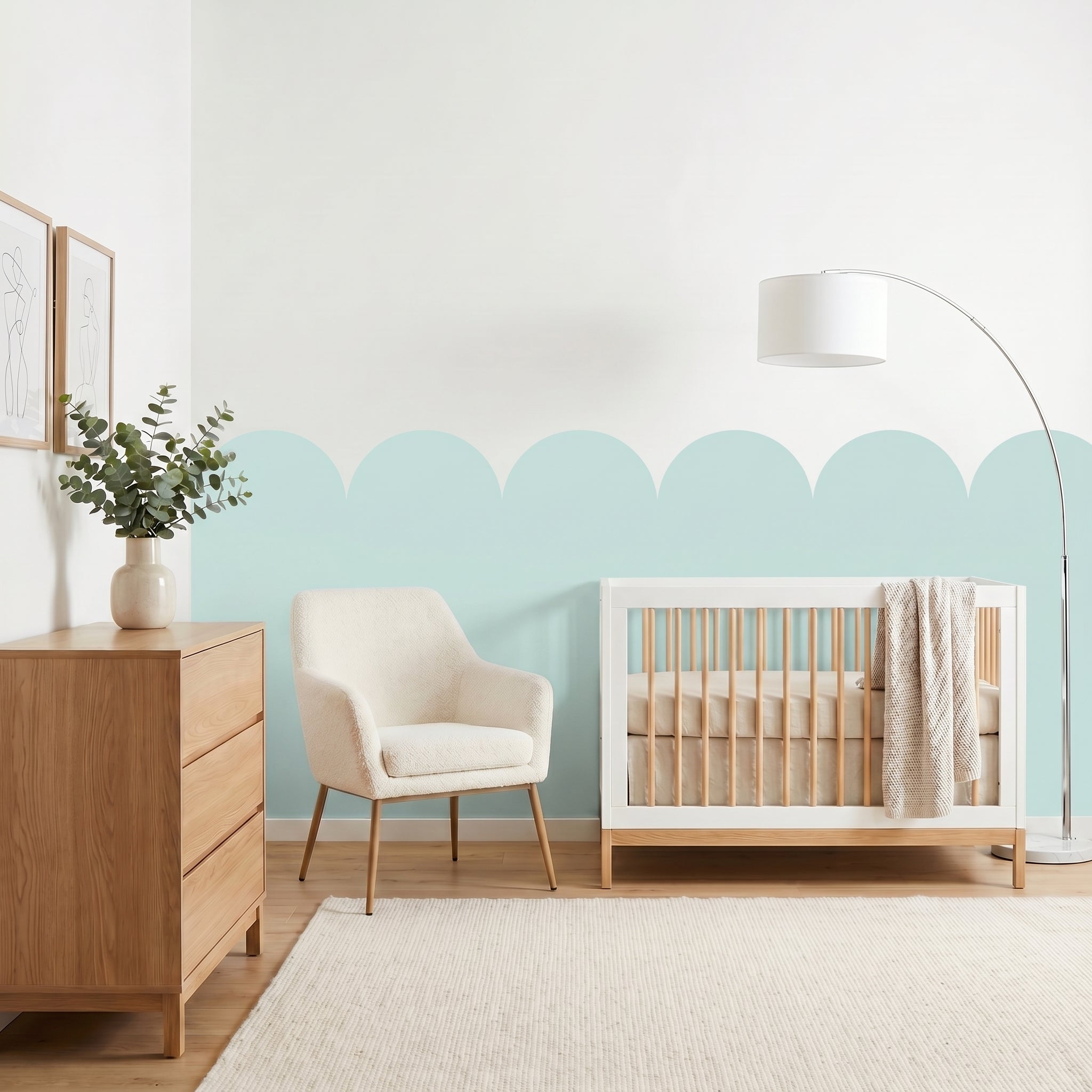 Nursery room with wooden crib, chair, and dresser against a light blue wall.