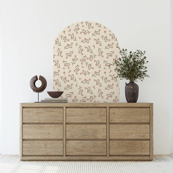 Wooden dresser with decorative items against a floral wall in a bright room.