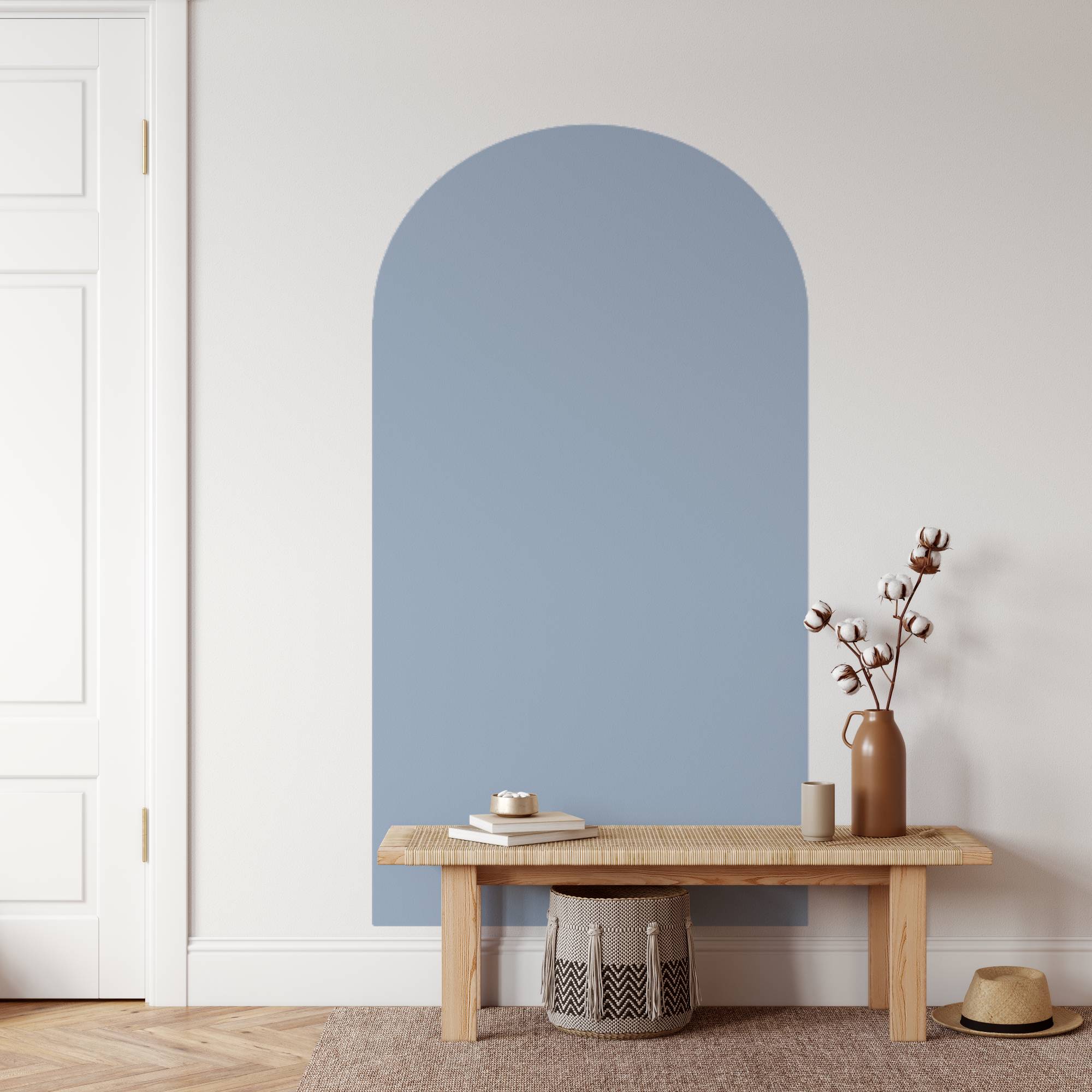 Arched blue mirror on a white wall with a wooden bench and decorative items.