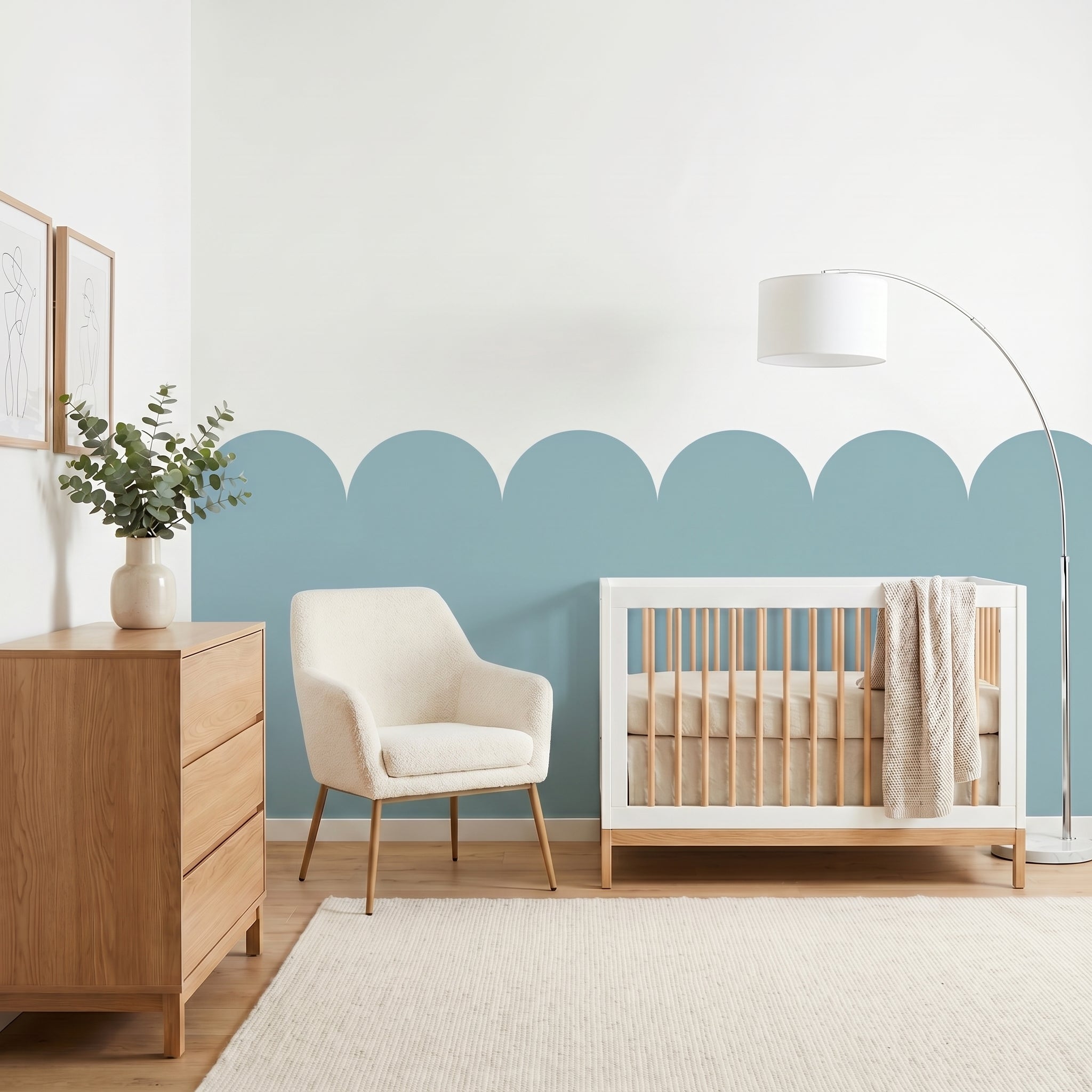 Nursery room with wooden crib, chair, and dresser against a light blue wall.