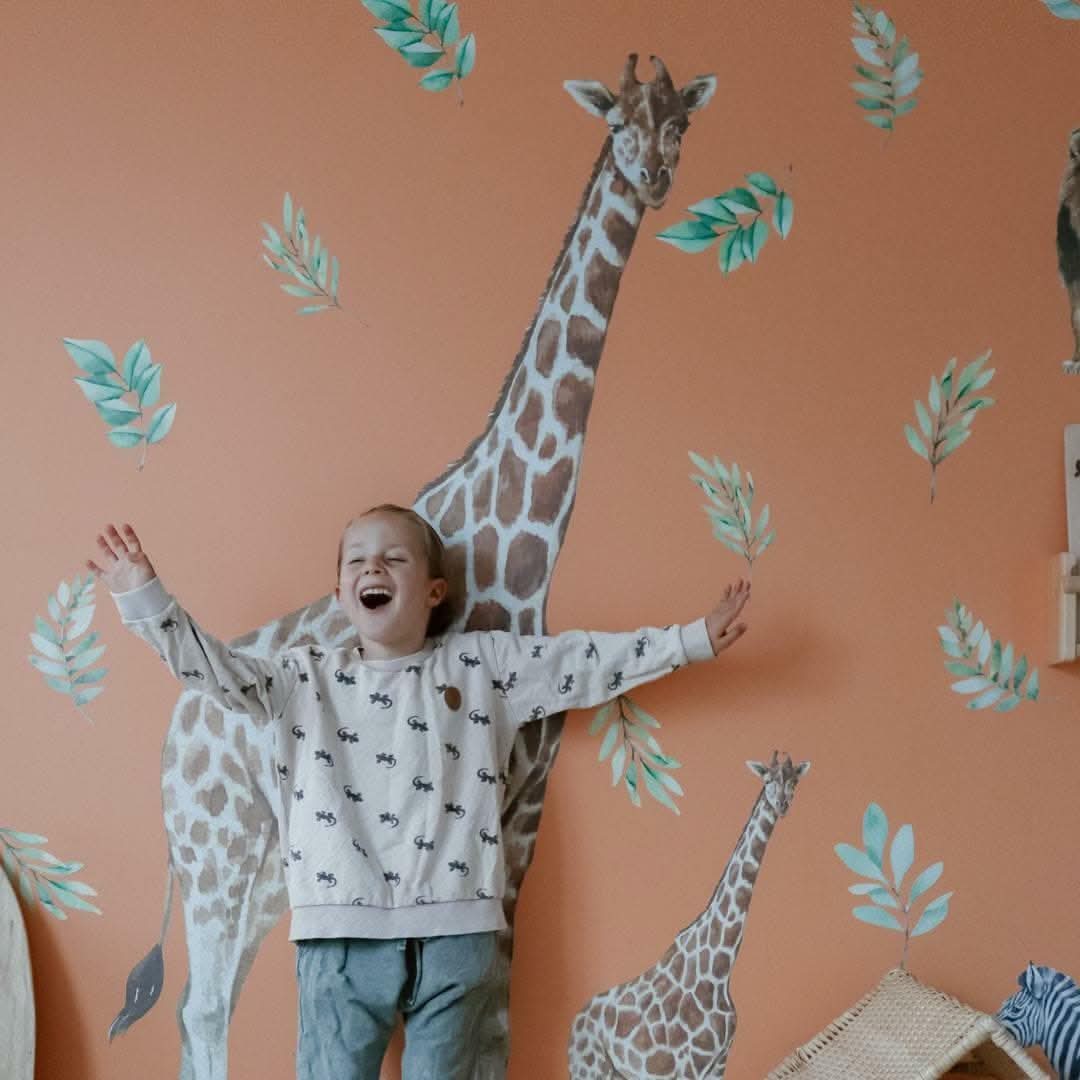 Child standing in front of giraffe decals on a terracotta wall