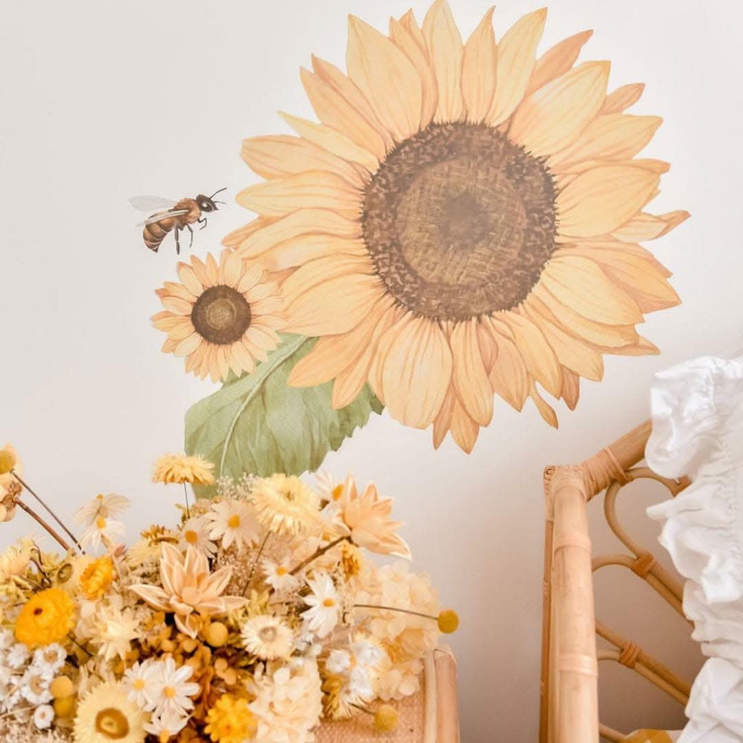Large sunflower wall decal with a bee above a display of dried flowers