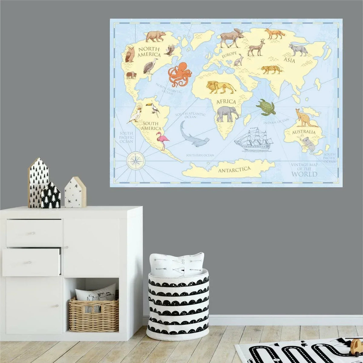 Vintage world map wall decal on a grey wall above white drawers